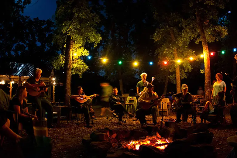 Adults singing around a campfire.